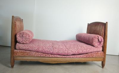 un lit recouvert d'une couverture rose, dans un coin de la pièce