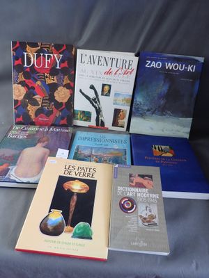 Plusieurs livres sont posés sur une table recouverte d'une nappe grise.