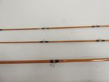 three wooden fishing rods are lined up against a white wall