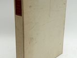 an old book sitting on top of a white table next to a white wall