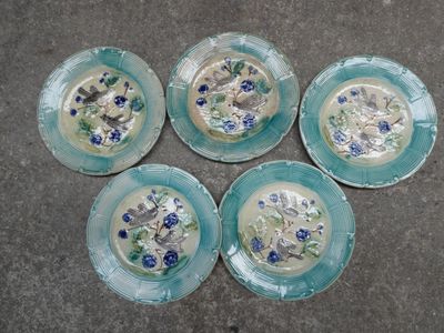 quatre assiettes bleues et blanches ornées de fleurs, posées par terre