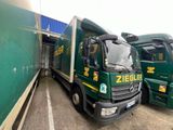 two green trucks parked next to each other in a parking lot