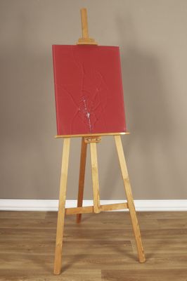 un chevalet sur lequel est posé un tableau rouge, dans une pièce