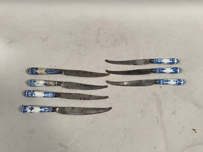Quatre couteaux sont posés sur une surface blanche ornée d'un motif bleu et blanc.
