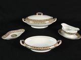 four pieces of white and gold china on a black background