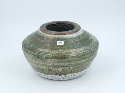 un vase vert muni d'une étiquette, posé sur une surface blanche
