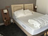 a bed with a white comforter and a chair in a room