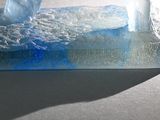 a blue liquid in a glass container with a wave coming out of it