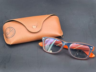 lunettes de soleil et étui posés sur une surface noire, avec un étui en cuir marron