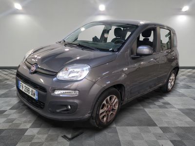 La petite voiture grise est garée sur un sol en dalles à damier.