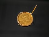 an image of a gold coin on a black surface with a yellow cord