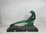 statue of a green bird sitting on a black base