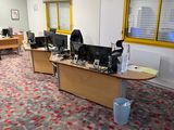 un tapis aux couleurs vives dans un bureau équipé de deux bureaux et de deux ordinateurs