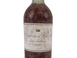 une vieille bouteille de vin posée sur une surface blanche