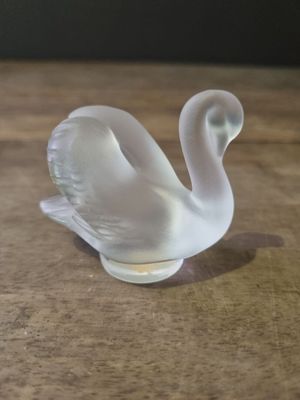 a glass swan that is sitting on a wooden table