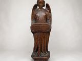 une statue en bois représentant un ange tenant un panier