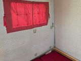 a small bed in a small room with a red sheet on it