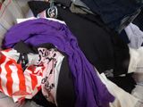 a pile of clothes that is sitting on a bed
