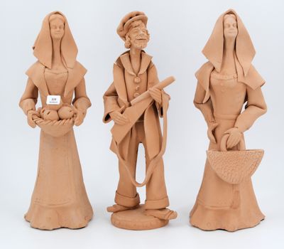 three clay figurines of a woman and a man holding a basket