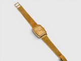 a close up of a gold watch on a white surface