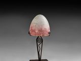 a lamp with a pink shade on top of a metal base