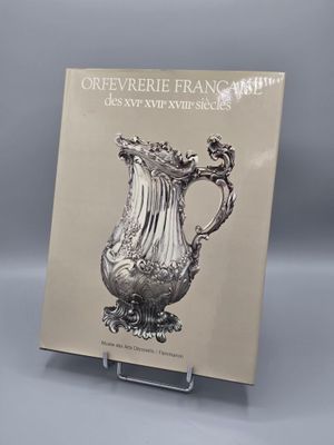 un vase ancien en argent exposé devant un fond gris