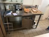 a kitchen with a stainless steel table and a metal trash can