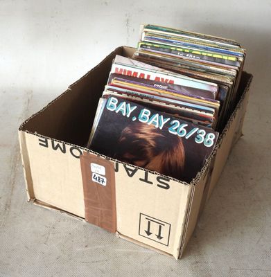 une boîte en carton remplie de disques de toutes sortes, posée par terre
