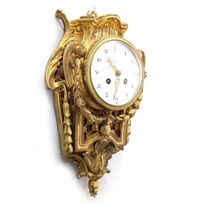 une horloge dorée sur un mur blanc, avec un fond blanc