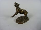 statue en bronze représentant un chien bondissant, posée sur un socle, sur une surface blanche