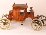 a small wooden horse drawn carriage on a white surface