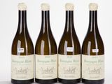three bottles of white wine are lined up on a table