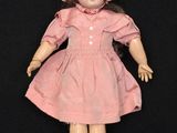 an old fashioned doll with a pink dress and bonnet on a black background