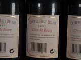three bottles of red wine are lined up on a shelf