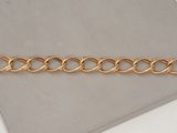 a close up of a gold chain bracelet on a white surface