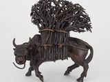 une statue représentant une vache portant un fagot de branches sur le dos