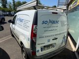 une camionnette blanche garée sur un parking, avec une échelle sur le toit