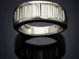 a white gold ring with baguets of diamonds on a black surface