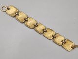 a close up of a gold bracelet on a white surface