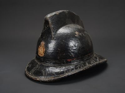 un vieux casque de pompier noir orné d'un insigne doré