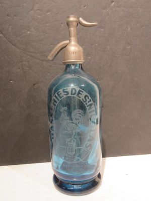 a blue glass bottle with a metal handle on a table