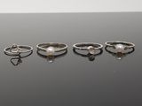 cinq bagues différentes ornées de perles et de diamants sur un fond noir