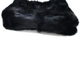 black fur pillow on a white surface with a white background