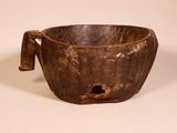 a brown bowl with a handle on a white surface