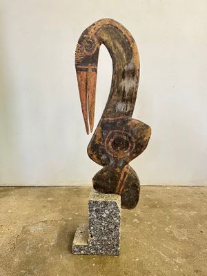 statue of a bird with a long beak on a stone block