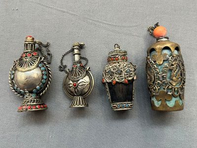 Quatre vases en argent aux motifs variés sont alignés sur une table