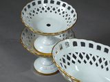 two white bowls with gold rims on a table