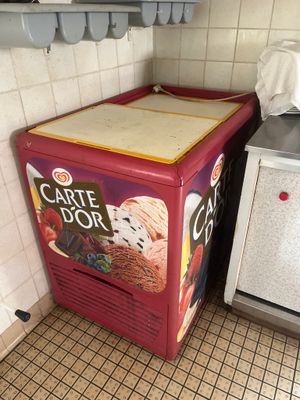 un réfrigérateur rouge sur lequel sont posées des glaces, dans une cuisine