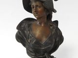 bronze bust of a woman wearing a hat and a dress