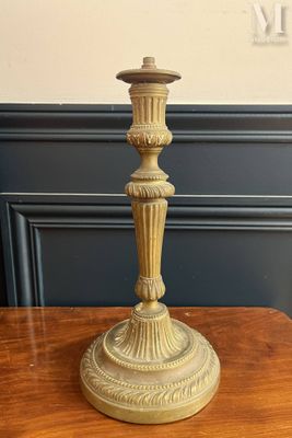 un bougeoir ancien en laiton posé sur une table en bois, avec un mur bleu en arrière-plan
